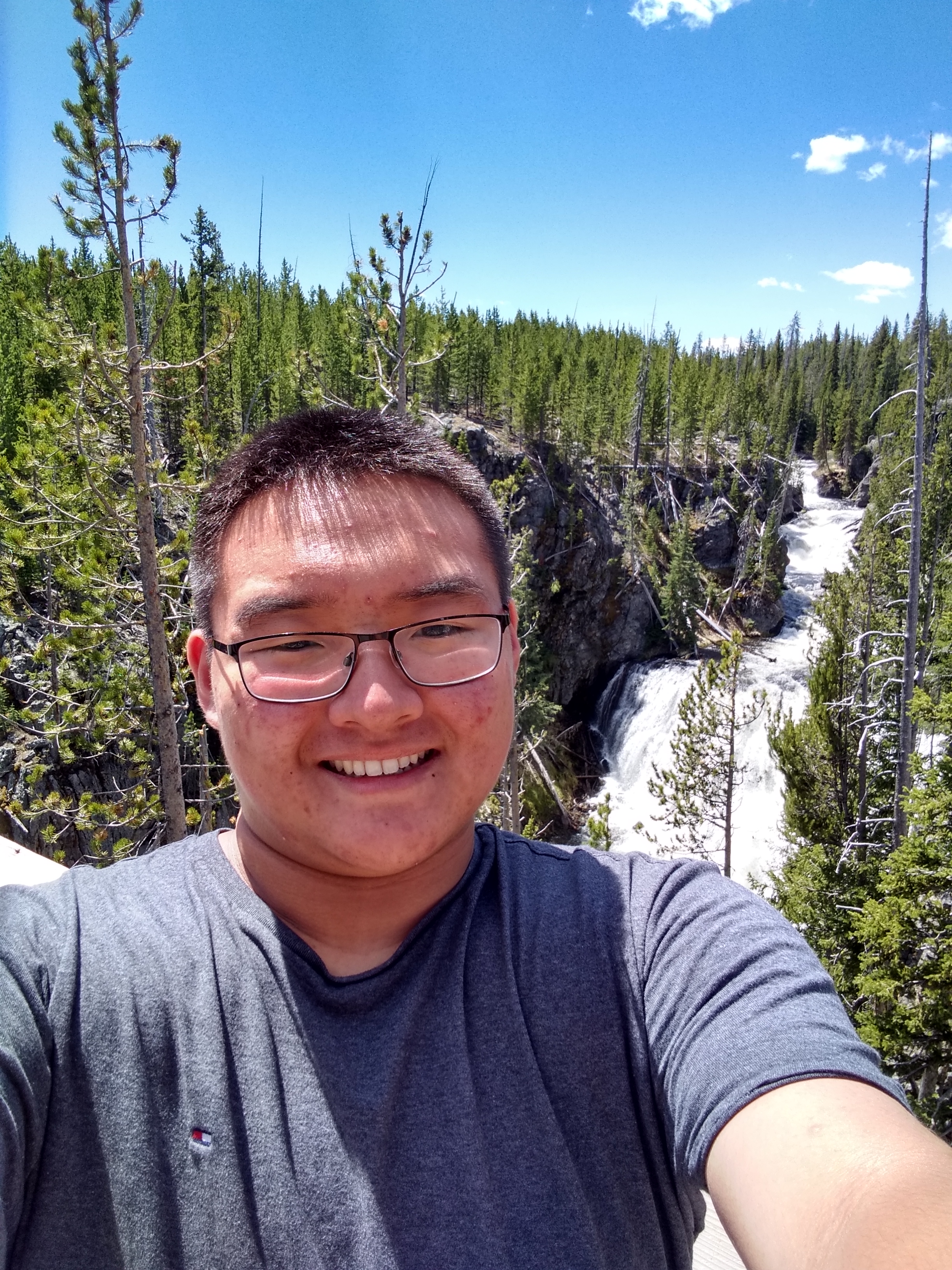 A picture of William Ko with a waterfall behind him